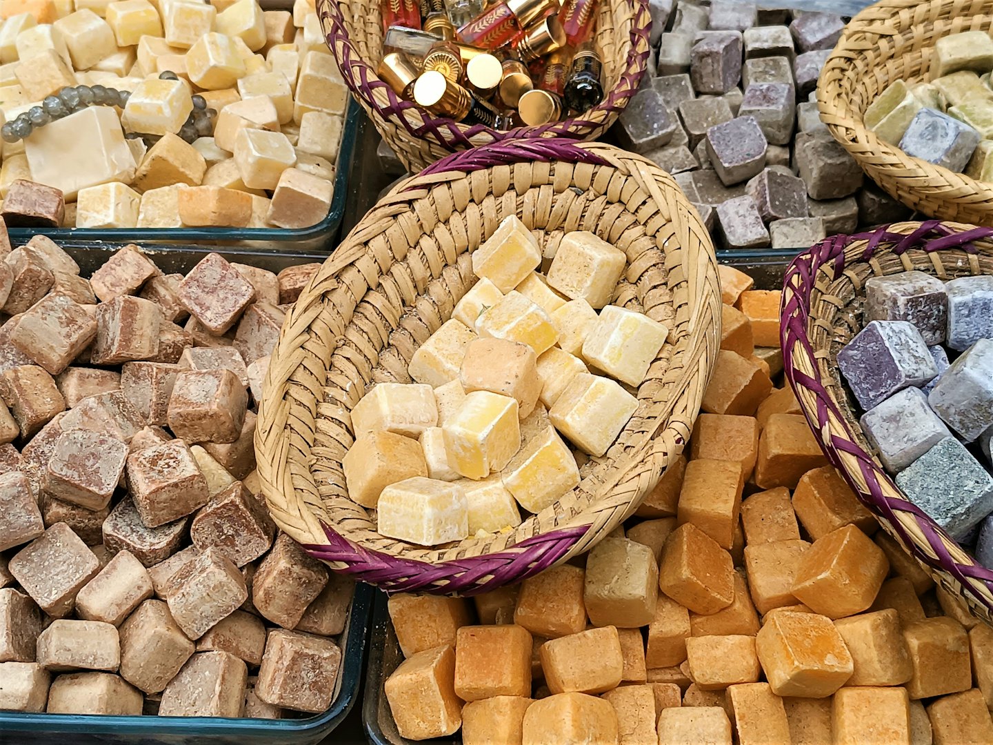 Handmade soap cubes arranged in woven baskets and glass trays.