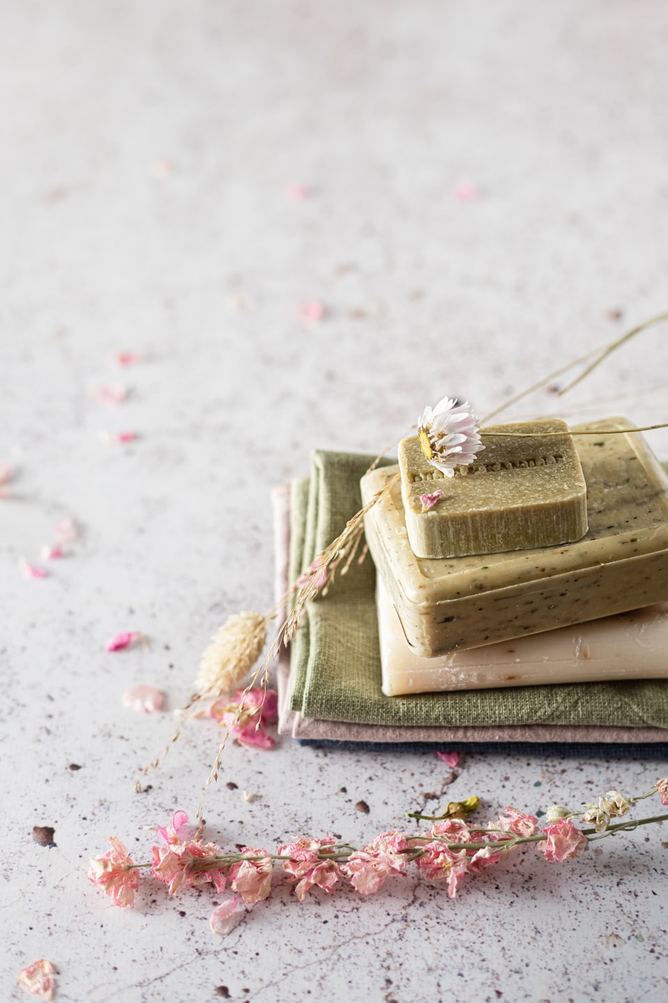 Handmade soaps with dried flowers and petals on a table.