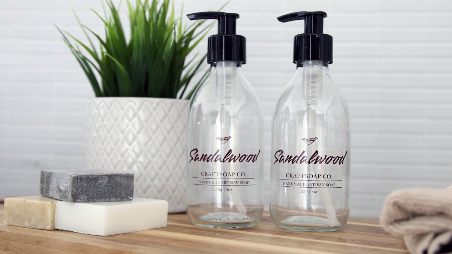 Artisan soap bottles and bars sit on a wooden counter.