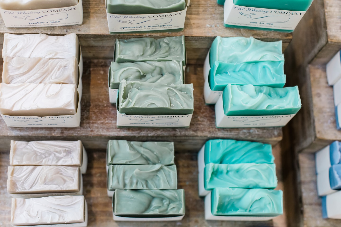 Handcrafted soaps in natural colors arranged on wooden shelves.