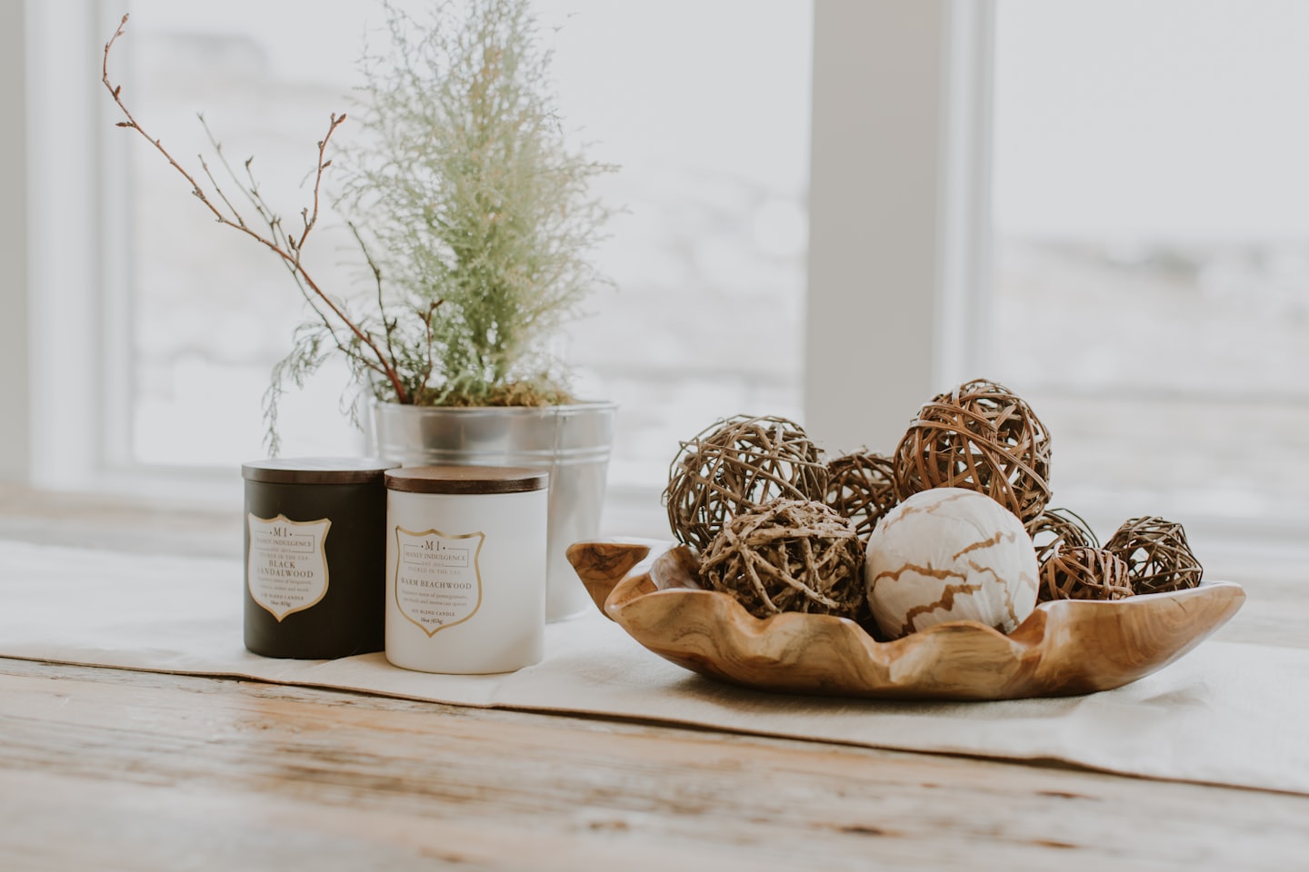 Scented candles and decor items arranged on a wooden table.