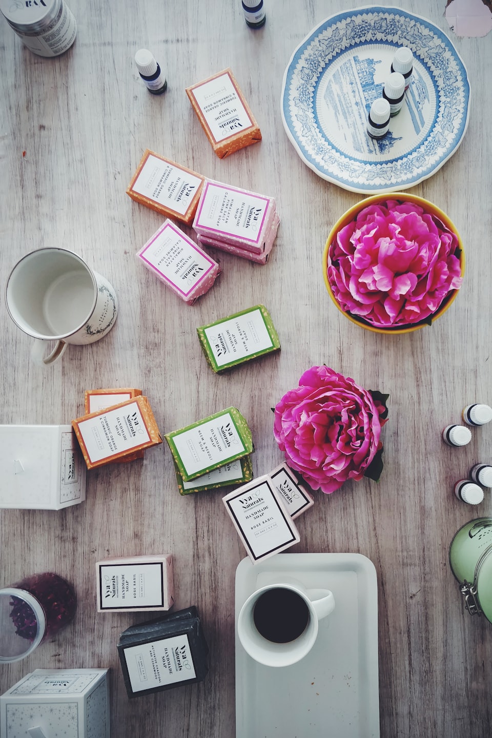 Handmade soaps and essential oils arranged with flowers and coffee.